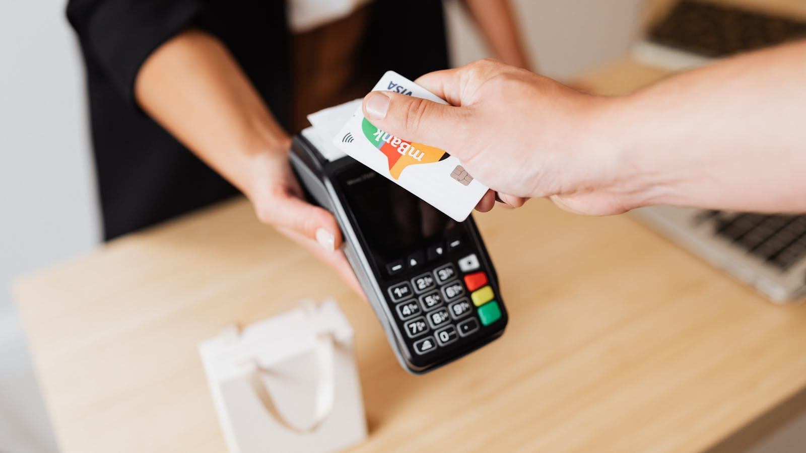 Customer making a contactless card payment on a modern POS terminal in-store