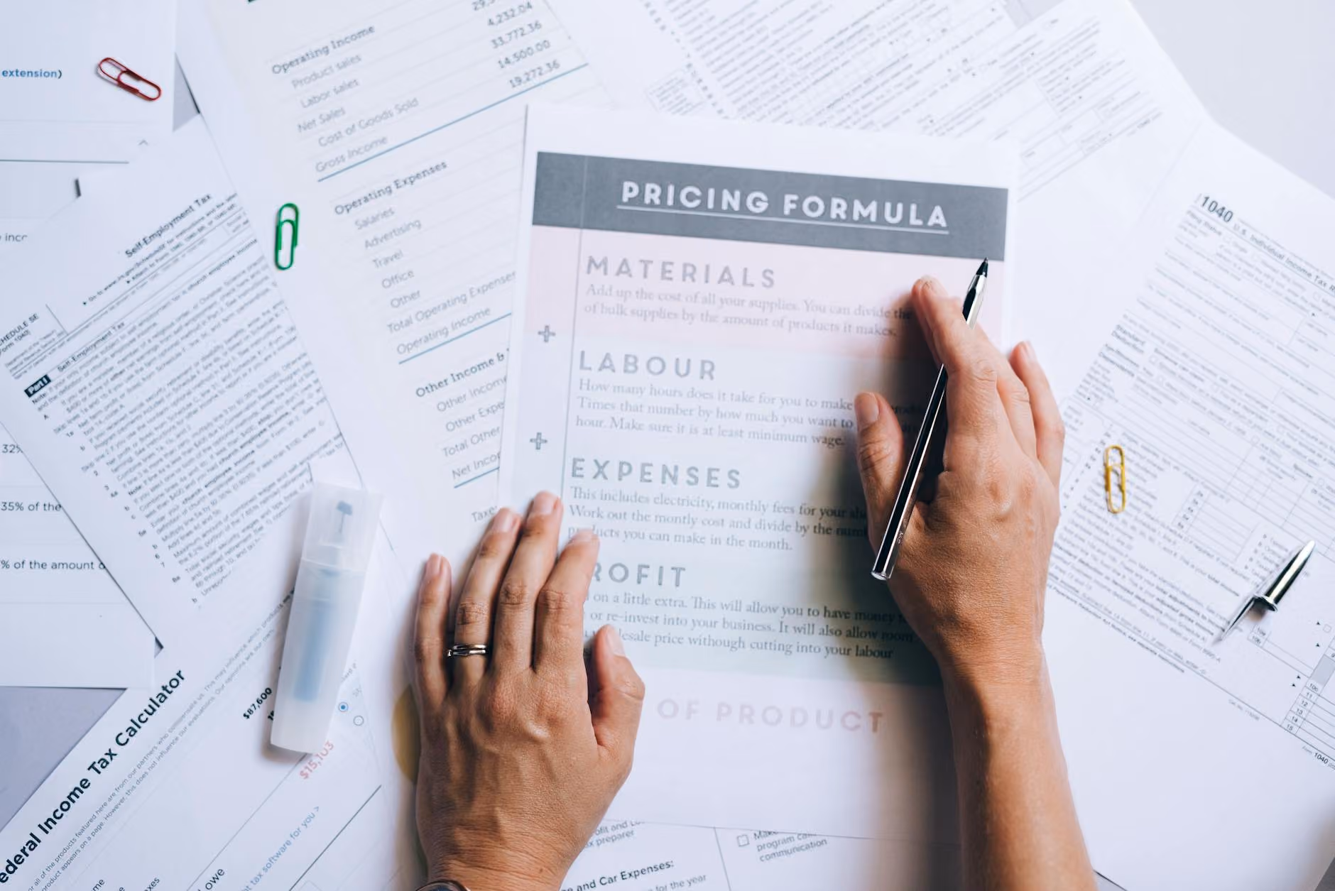 Hands organising business documents and pricing papers on a desk